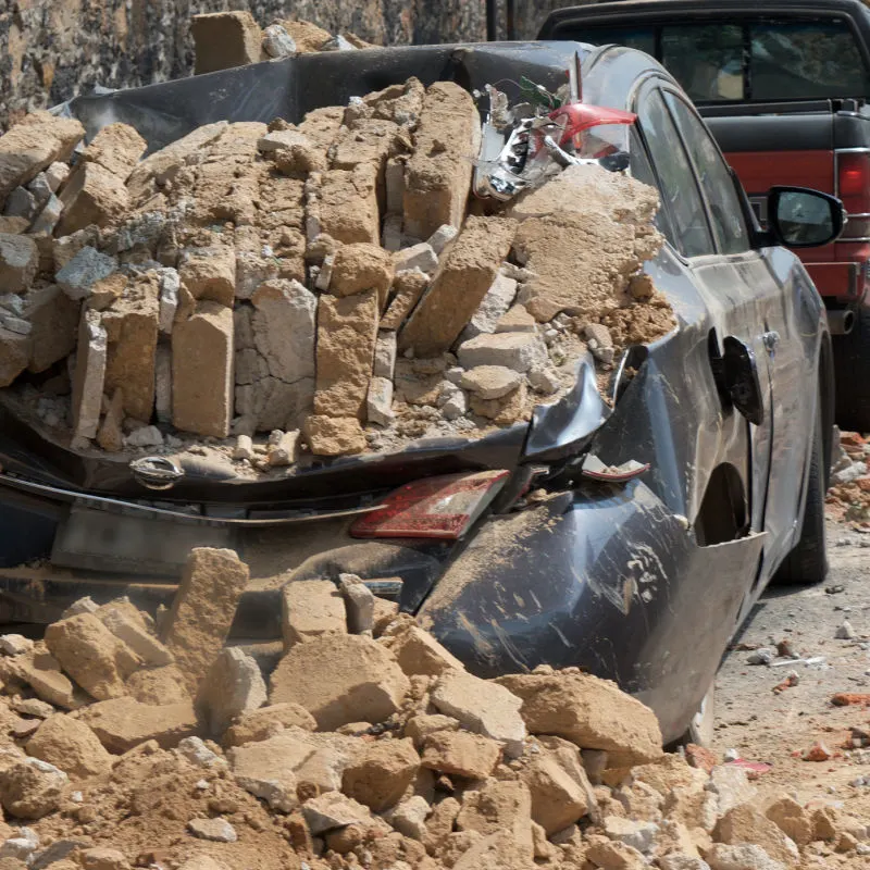Car covered in debris and rubble following an earthquake