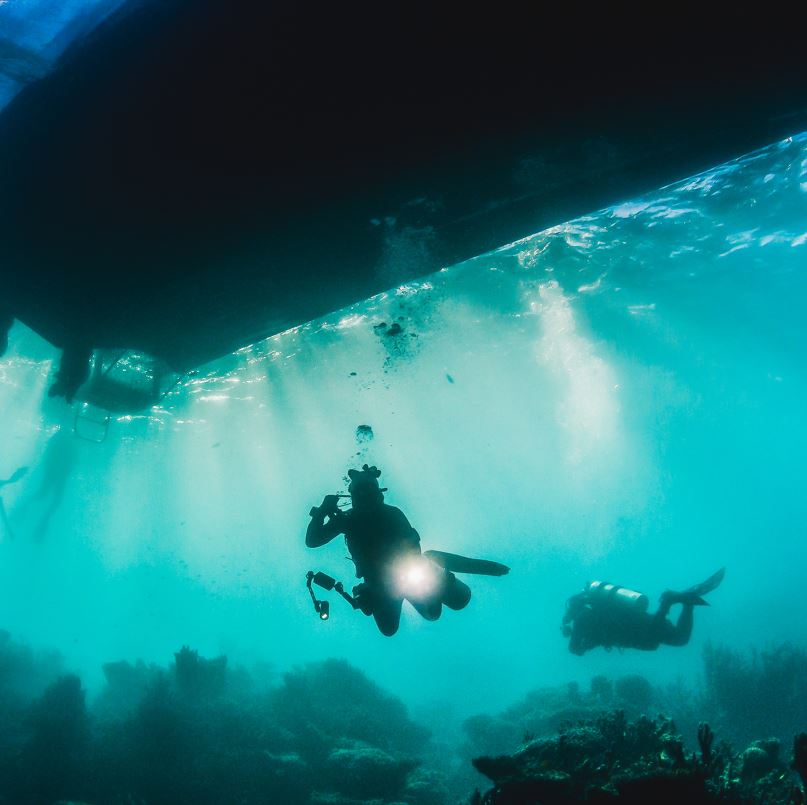 Divers below a boat in the ocean