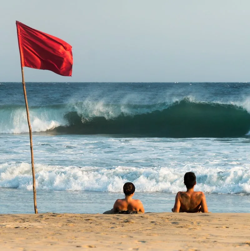 Tourists looking at an incoming wave at the beach