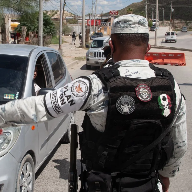 national guard member stopping a car on a dirt road