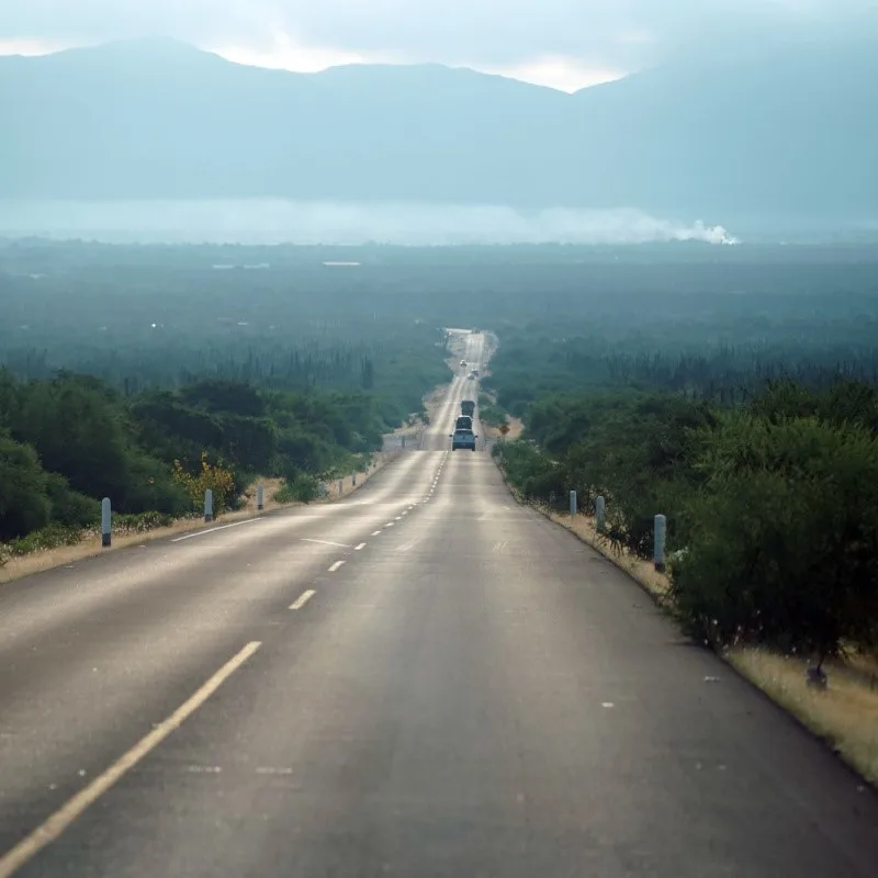 Road Leading to San Jose del Cabo with Cars on the Road and Hills in the Background