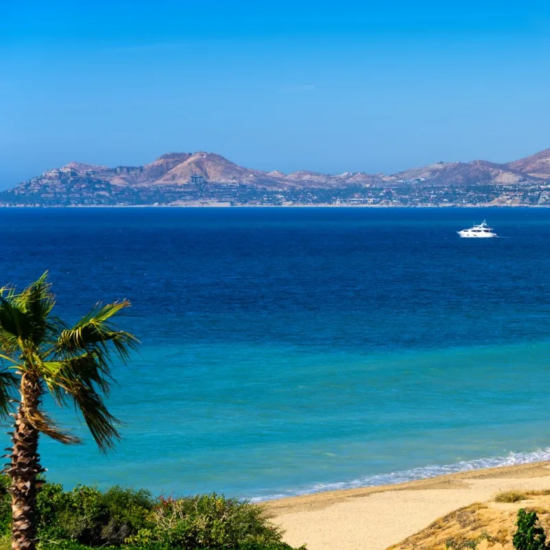 Small Los Cabos Coastline with a Yeacht on the Water and Hills and Buildings in the Background