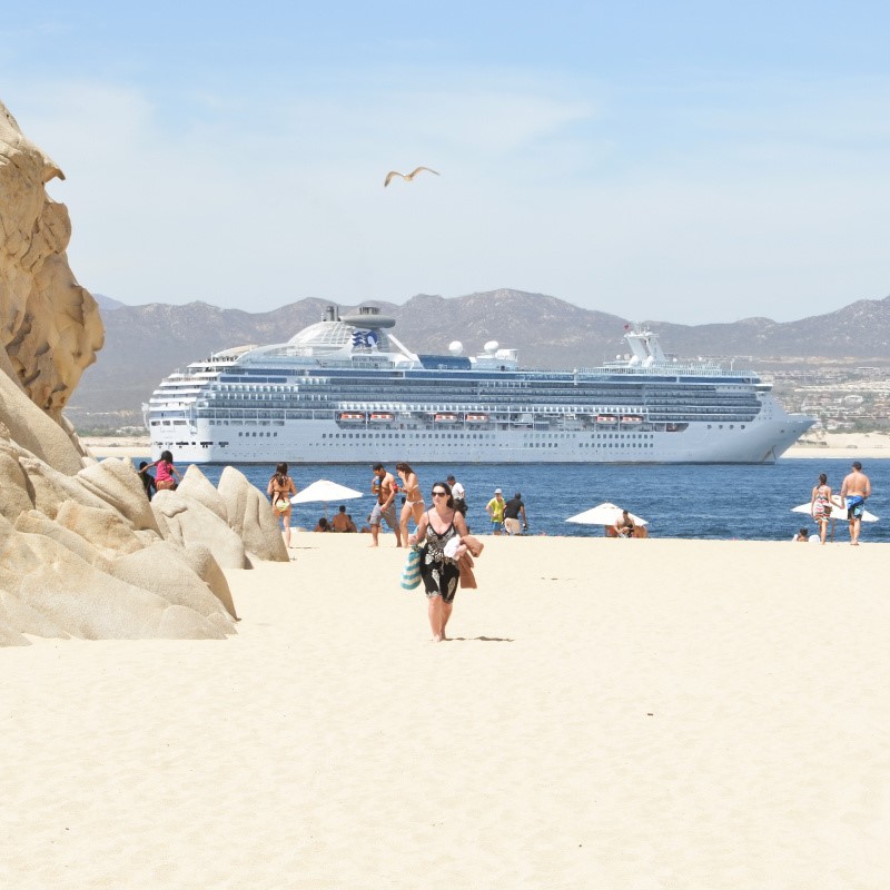 Tourists on a Sunny Beach in Cabo San Lucas with a Cruise Ship in the Background