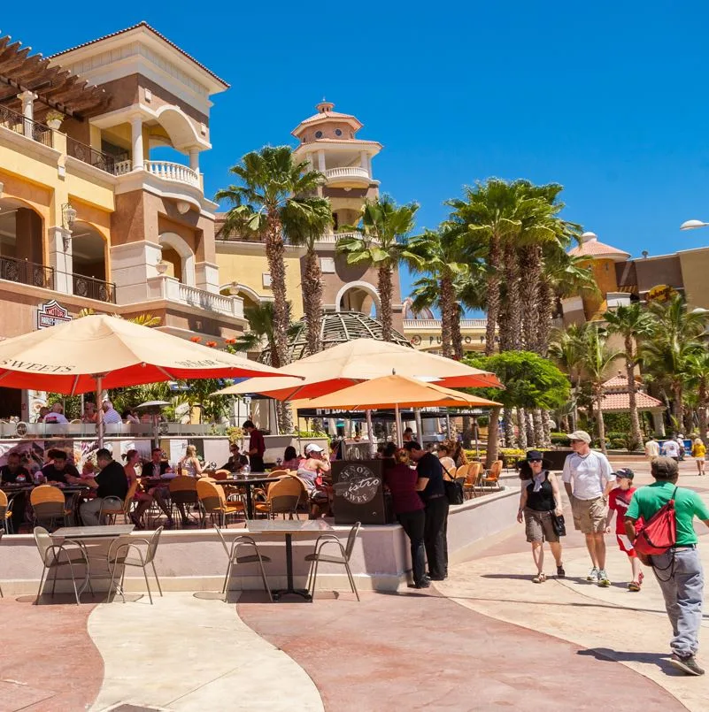 Tourists walking along the marina next to a restaurant in los cabos