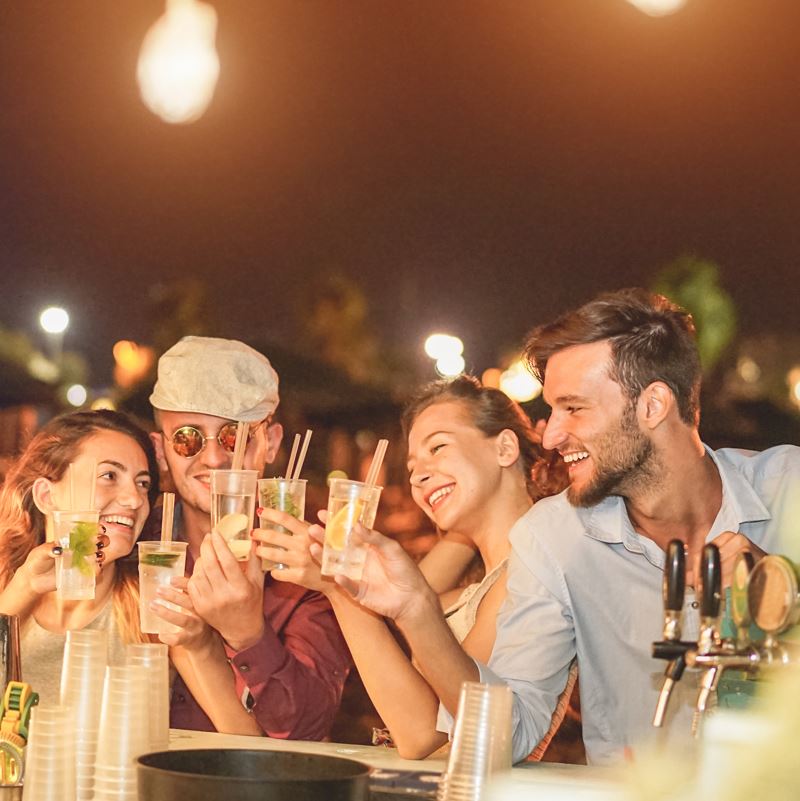 Young people cheers each other at a bar on a beach