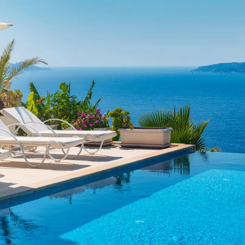 Beach chairs next to an infinity pool with the ocean in the background