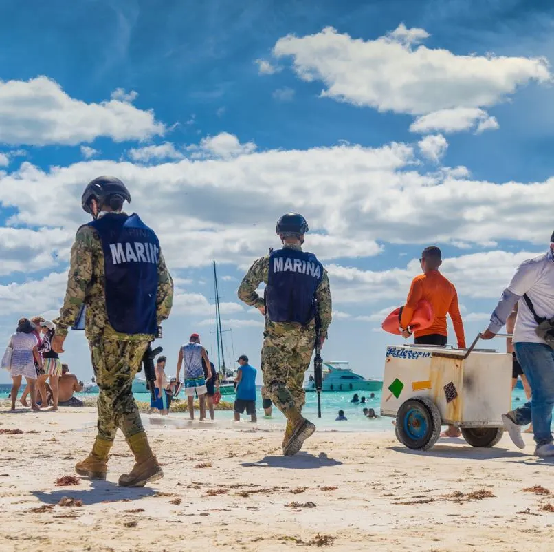 Mexican Marines Patrolling The Beach Alongside A Man Selling Popsicles