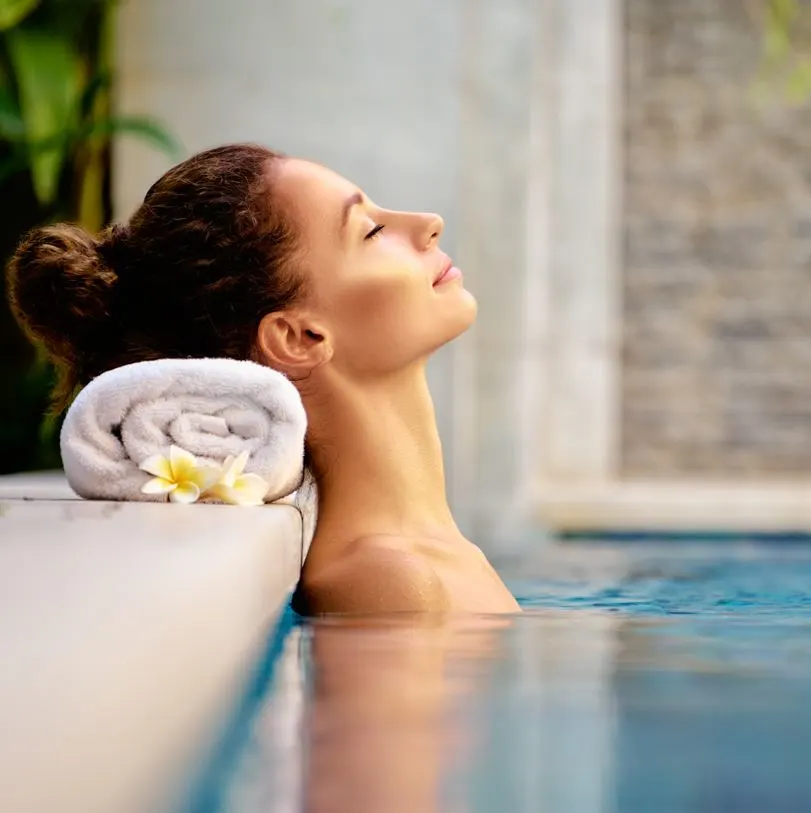 Woman resting her head on a towel on the side of a pool