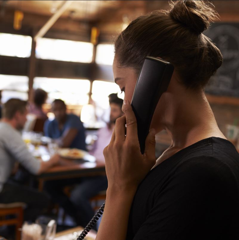 Hostess at a restaurant taking a reservation from a phone call