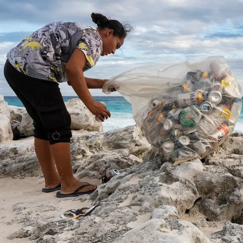 Volunteer collecting recyclable cans at a beach