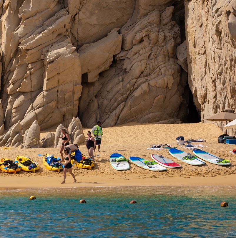 Surf boards and people with a lifeguard at Las Viudas beach in Los Cabos