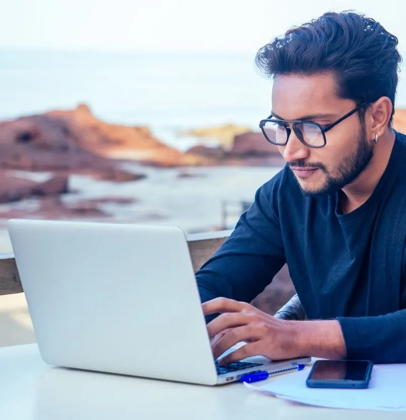 Man working on a laptop overlooking the beach