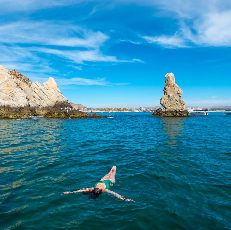 Woman floating in ocean near Lands End in Los Cabos