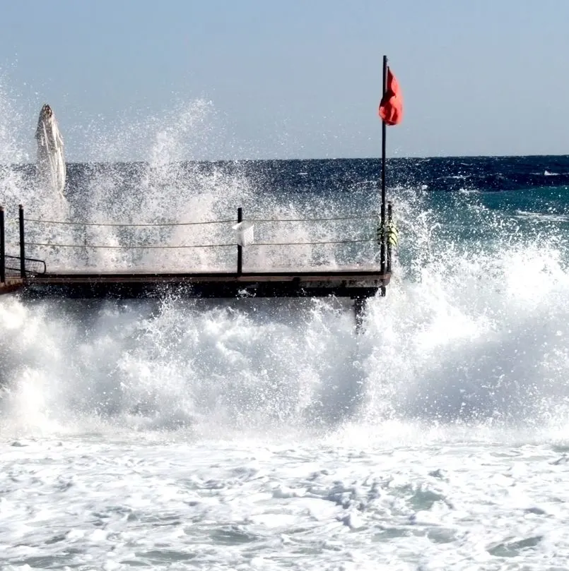 Large Waves Hitting A Dock With A Red Flag