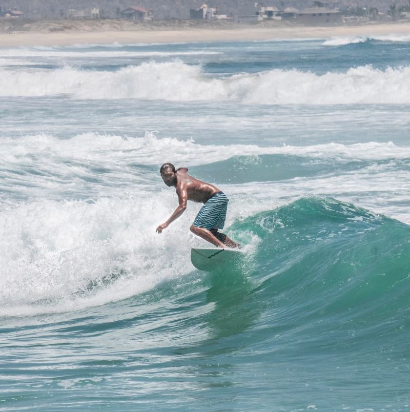 Man surfing the pacific ocean waves at Los Cerritos beach, Todos Santos, pueblo magico or magic town