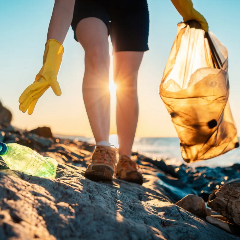 person picking up trash on the beach