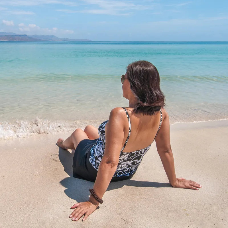 Woman Sitting Near the Water on a Beach