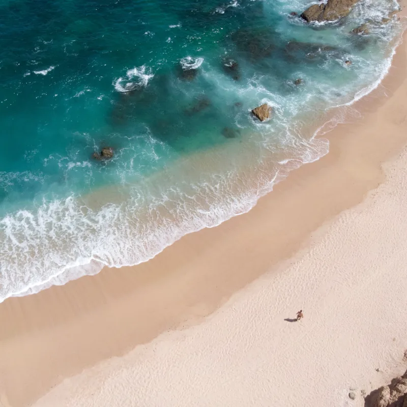 Aerial view of Chileno Beach in Los Cabos with man walking in the sand