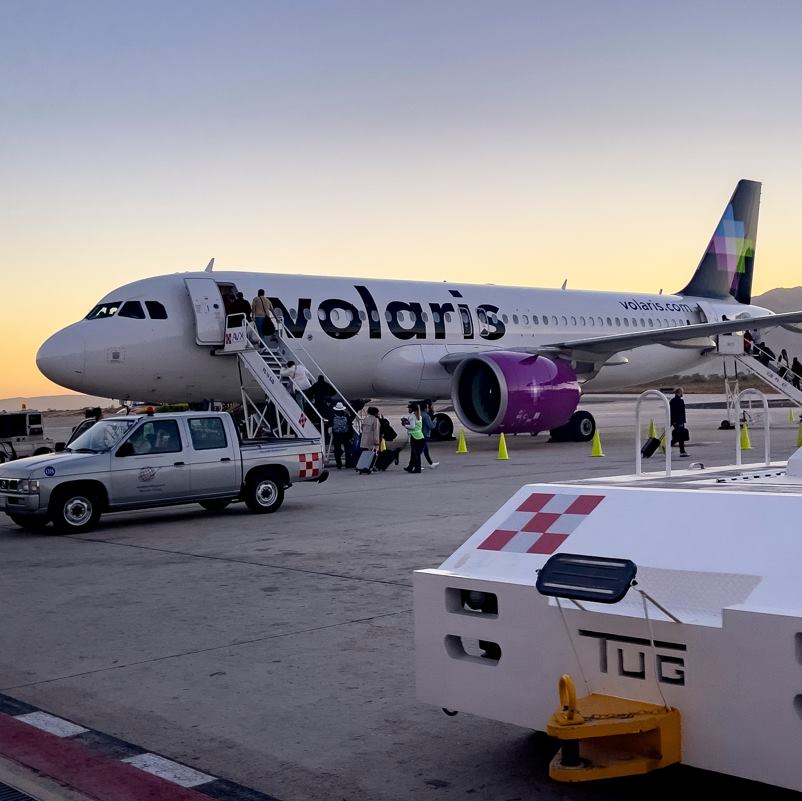 Volaris airplane loading passengers at an airport