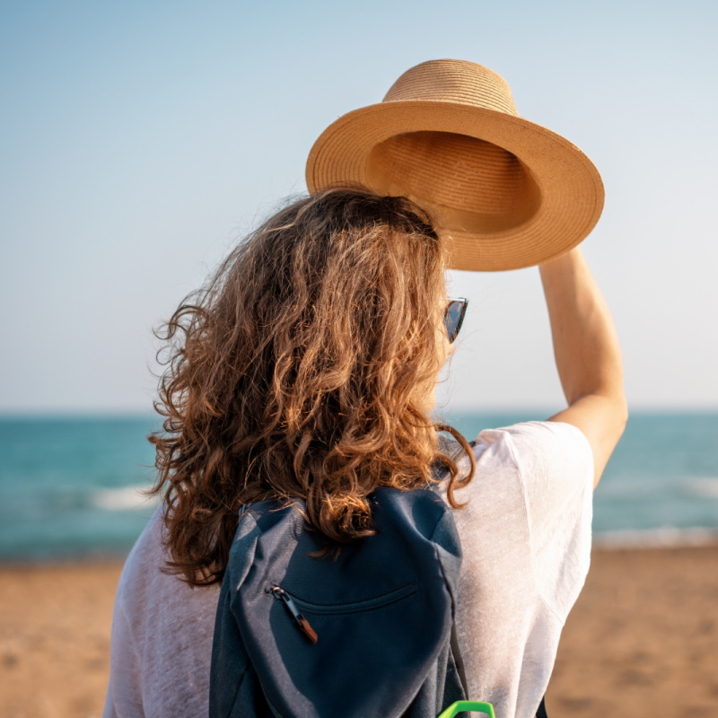 Woman with backpack and hat at the beach