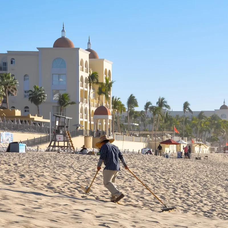 man cleaning beach with rake