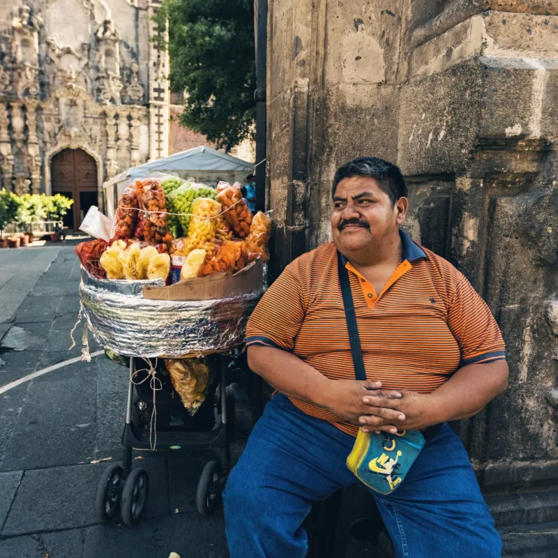 man sitting next to food cart