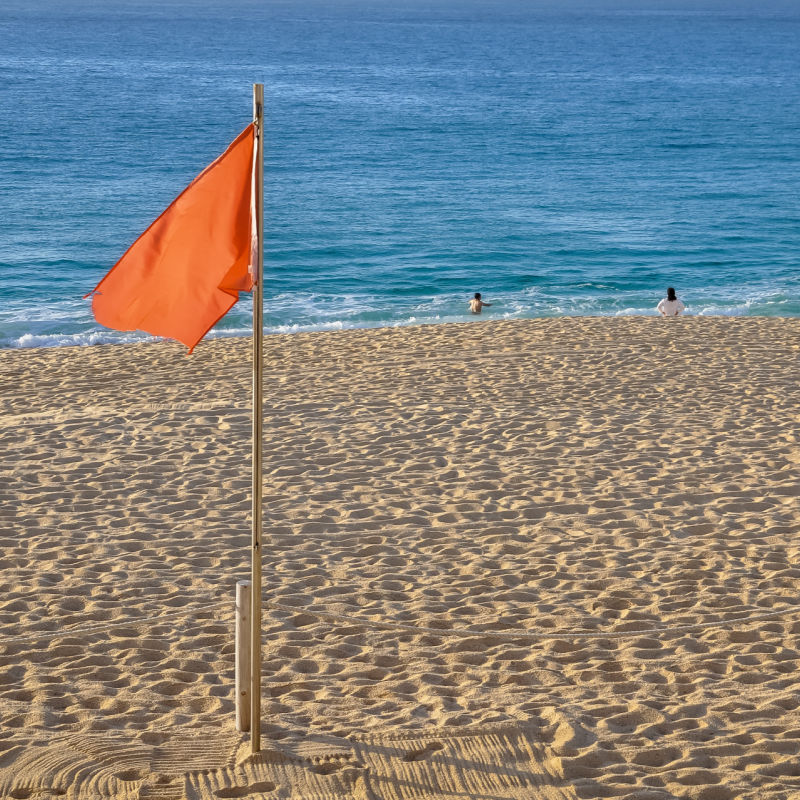 red flag on a sandy beach in cabo