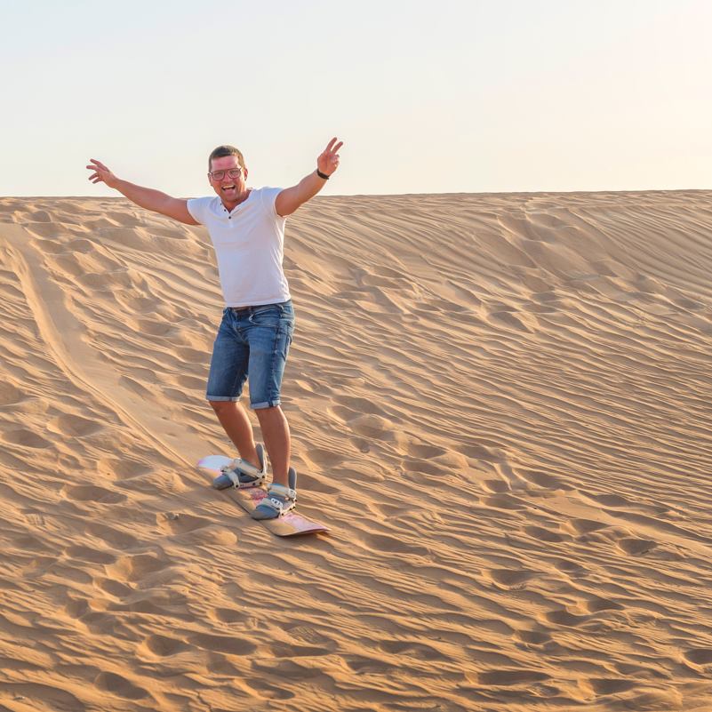 A man sandboarding on a dune