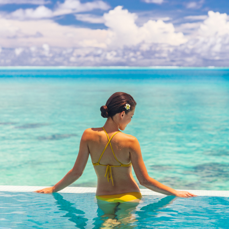 woman in pool overlooking beach