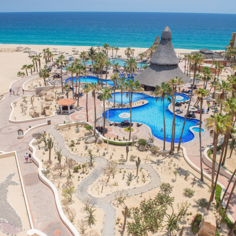 Aerial view of the pool with giant palapa, the Pacific Ocean from the SANDOS Finisterra hotel. los cabos