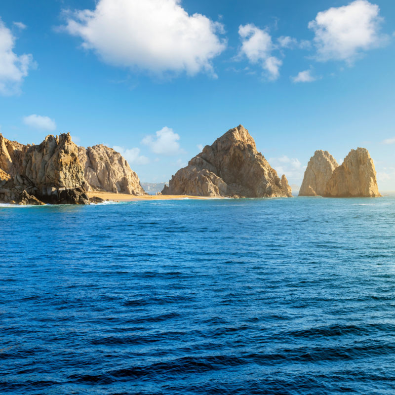 Sea view as sunlight hits the sandy Playa de Los Amantas, also known as Lover's Beach at the Land's End Los Arcos rock formation at Cabo San Lucas, Mexico.