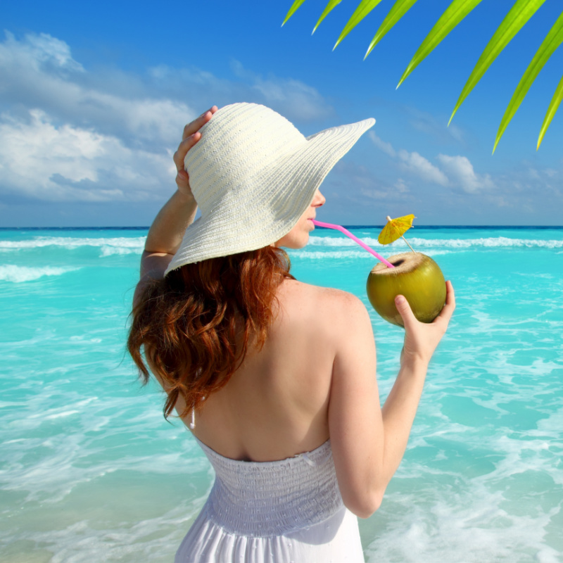girl at beach drinking from coconut