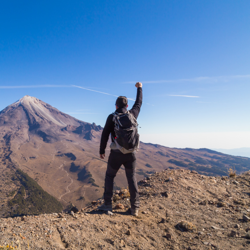 hiker standing on mountain with fist in the air