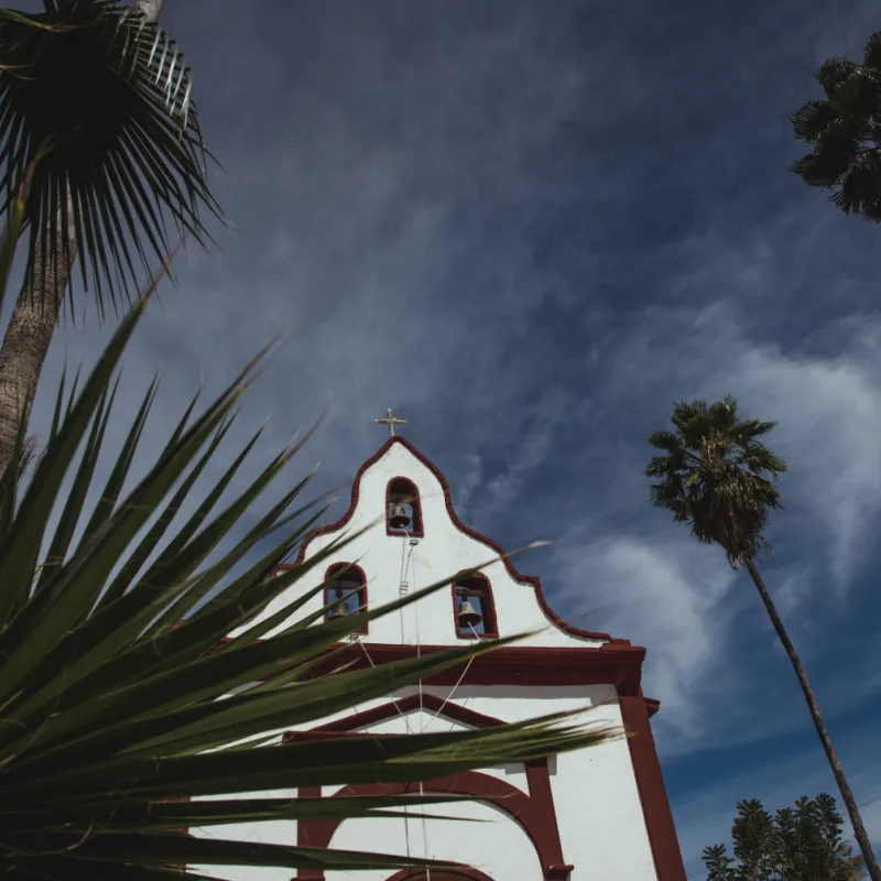 Low-angle-view-of-Miraflores-Church-seen-from-behinh-a-palm-leave.-East-Cape-region-of-Los-Cabos