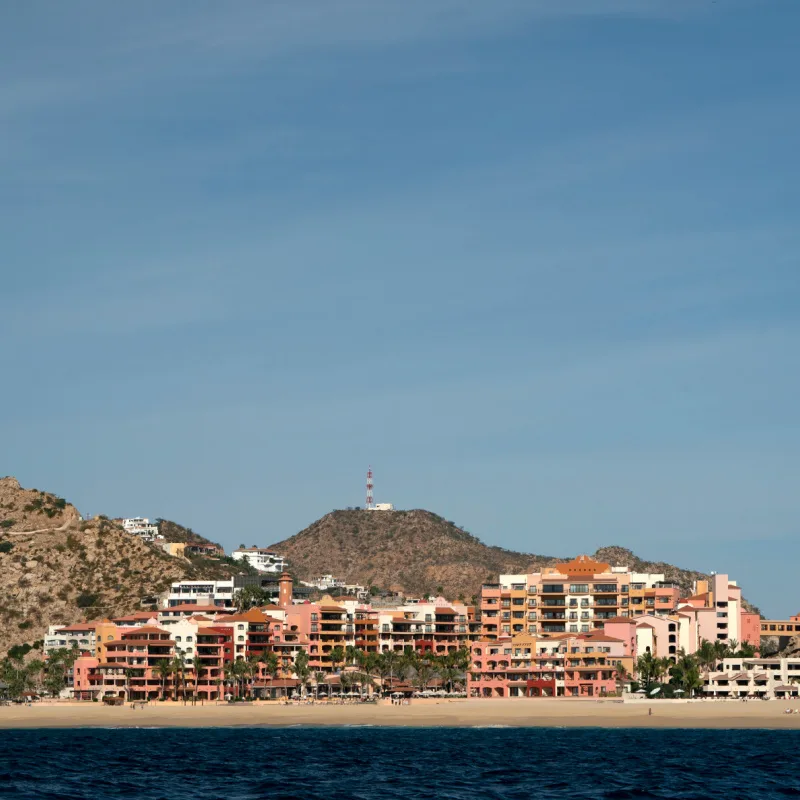View of a beach in Cabo San Lucas seen from the ocean. Accommodations in the distance