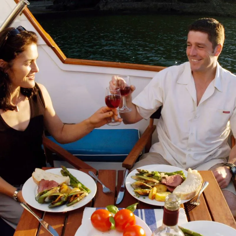 A couple toasting while eating a meal on a yacht