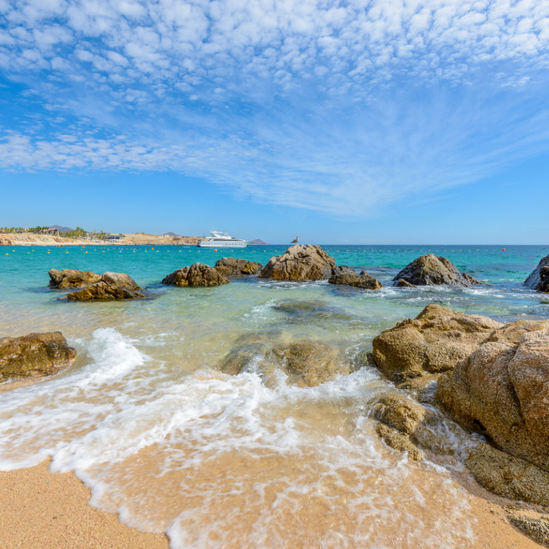 Fantastic sky, ocean and rocks. Differen stages of the waves on the ocean sand. Playa El Chileno Beach, Cabo San Lucas, Mexico.