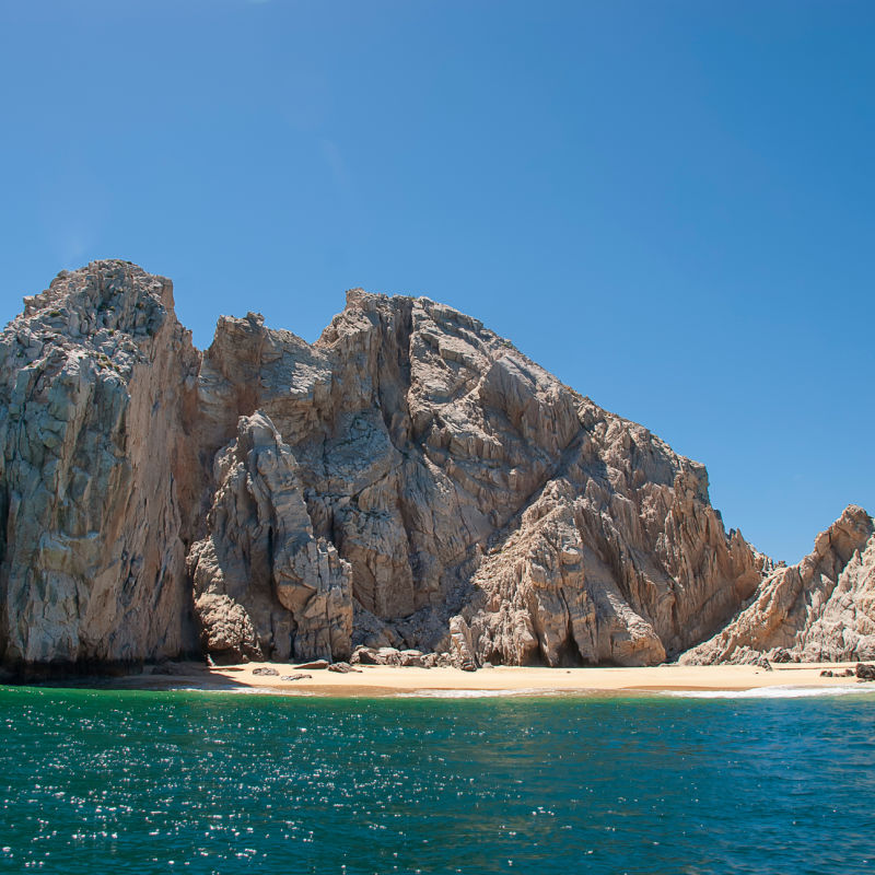 Rocks in Los Cabos with calm sea and little beach on a sunny day