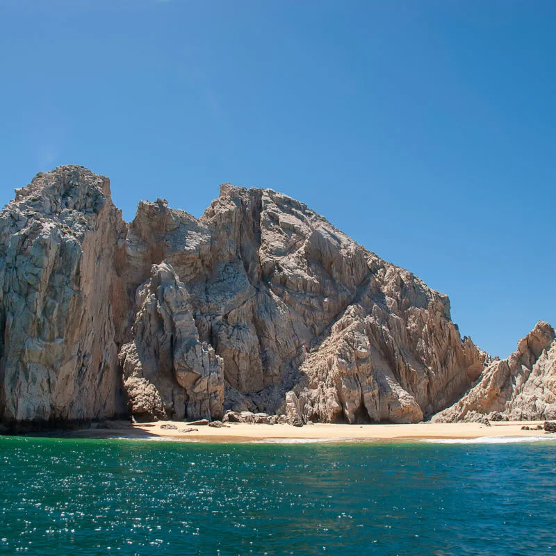 Rocks in Los Cabos with calm sea and little beach on a sunny day