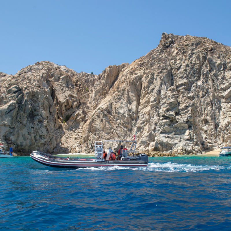 Tourist boats near Playa del Amor in Los Cabos, with mountains, clear blue sky and turquoise blue sea on summer vacation.