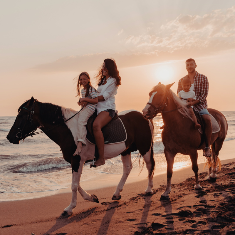 A family horseback riding on the beach