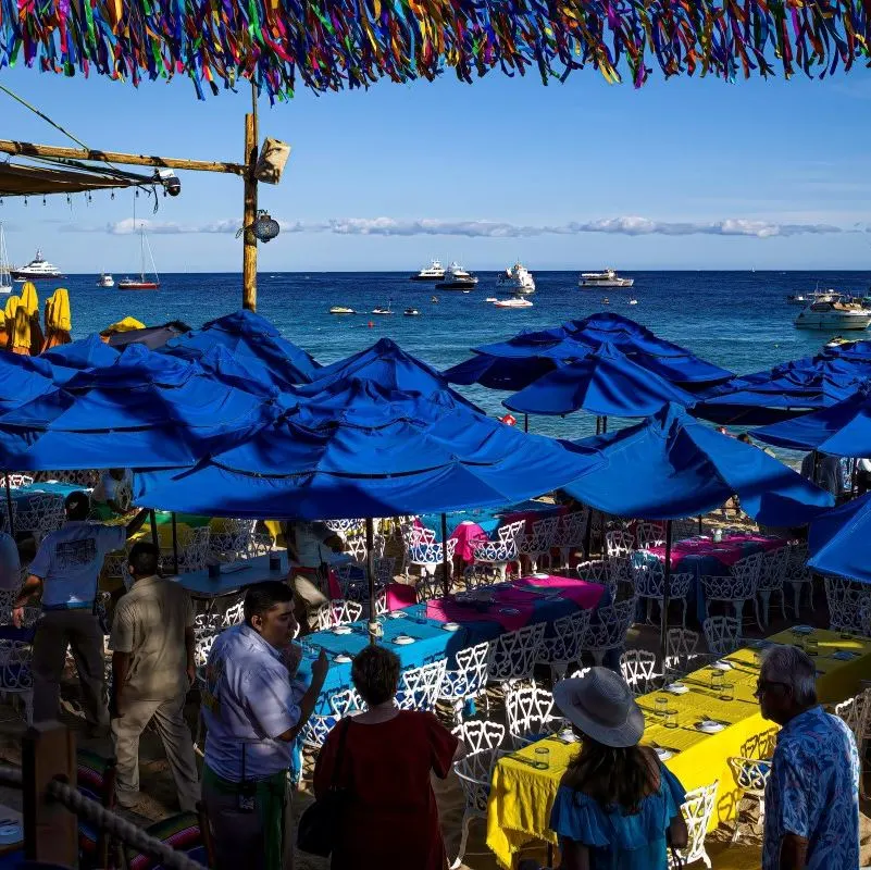 View from La Oficina restaurant of diners, tables and the ocean with boats beyond in the popular Medano Beach area.