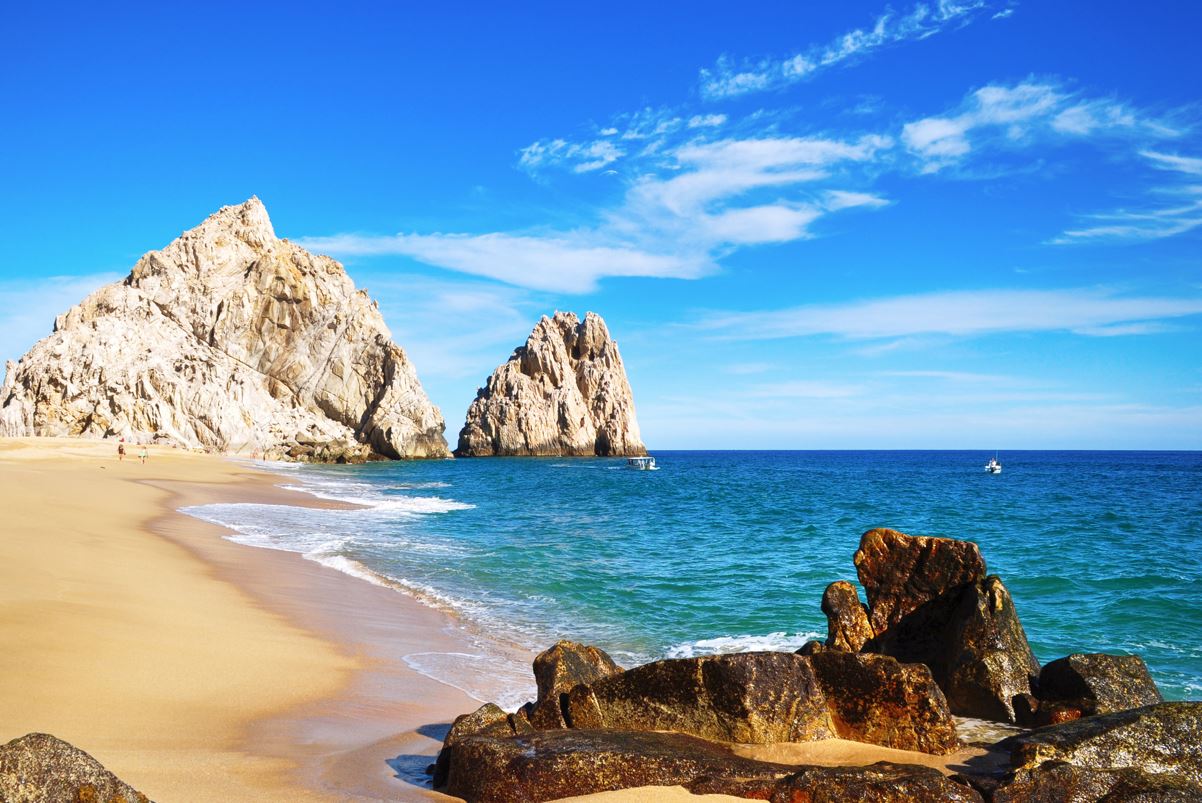 A view of a beautiful rock formation jutting into the sea from a los cabos beach