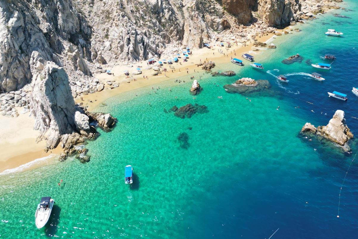 An exclusive cliff bottom beach in Los Cabos with clear waters and boats