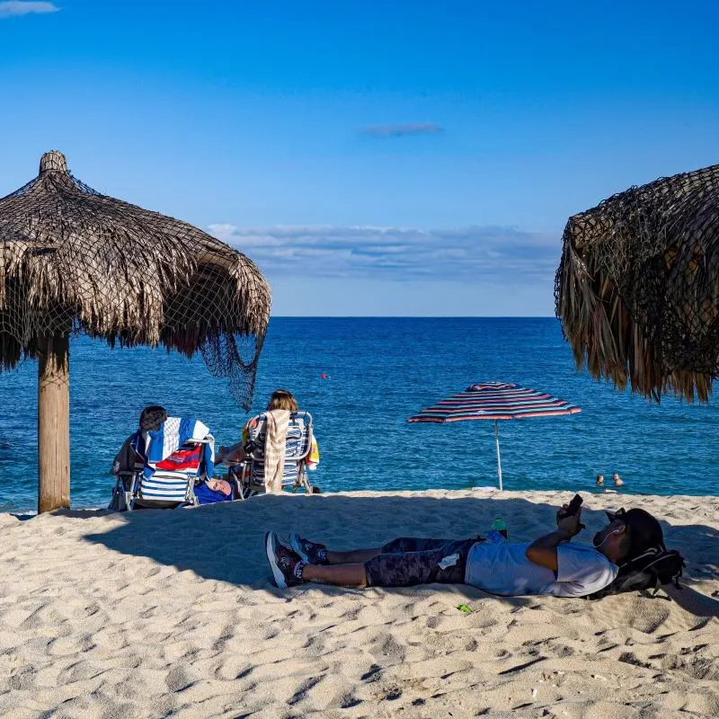 Beachgoers Sitting Under Palapas on Palmilla Beach in Los Cabos, Mexico