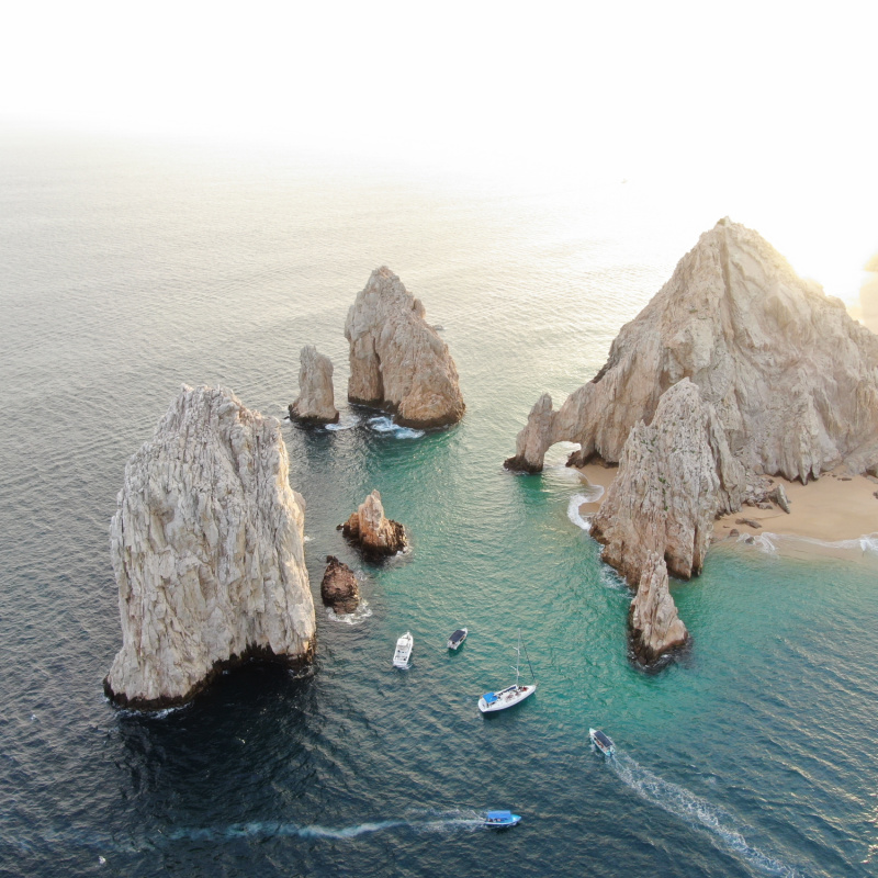 Aerial of stone arch and rocky cliffs in Cabo San Lucas, Mexico at sunset