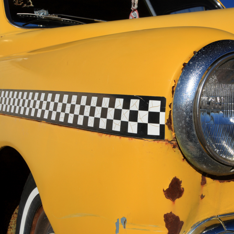 Close up of front fender and headlight of an 1950 automobile with checkered stripe found in New Mexico on Route 66