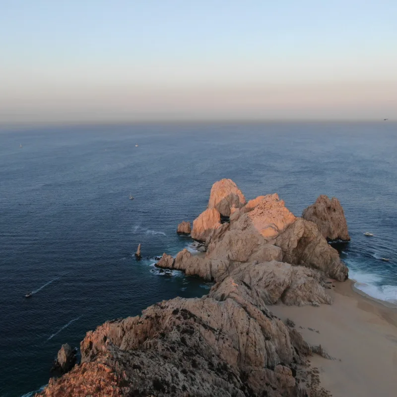 Aerial of stone cliff peninsula in Cabo, Mexico looking at Pacific Ocean