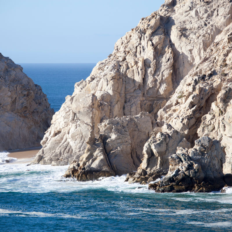 Lovers' Beach surrounded by steep rocks and hidden under waves in Cabo San Lucas resort town (Mexico).