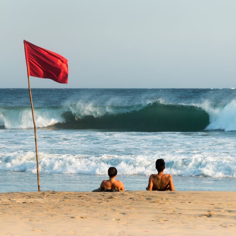 Tourists Next to a Red Beach Warning Flag on a Los Cabos Beach